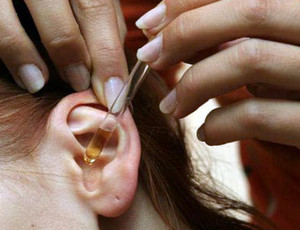 Женщина капает в ухо из пипетки