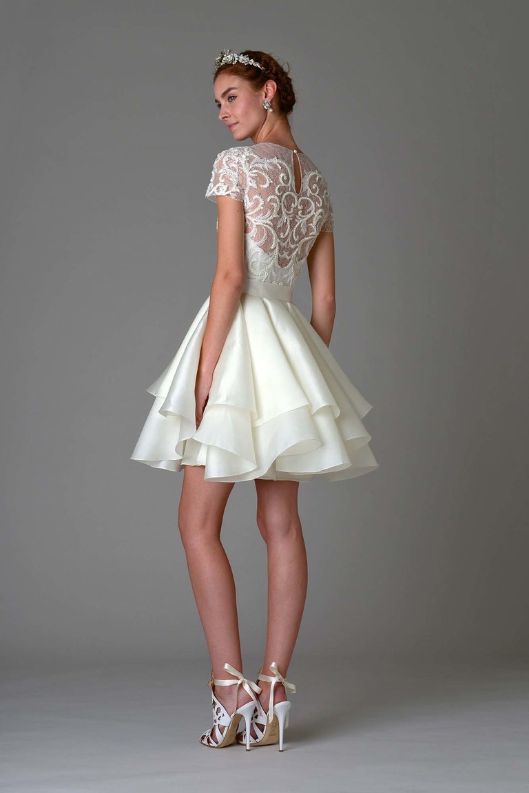 Короткое многослойное белое свадебное платье с кружевным орнаментом на спине из коллекции Marchesa.