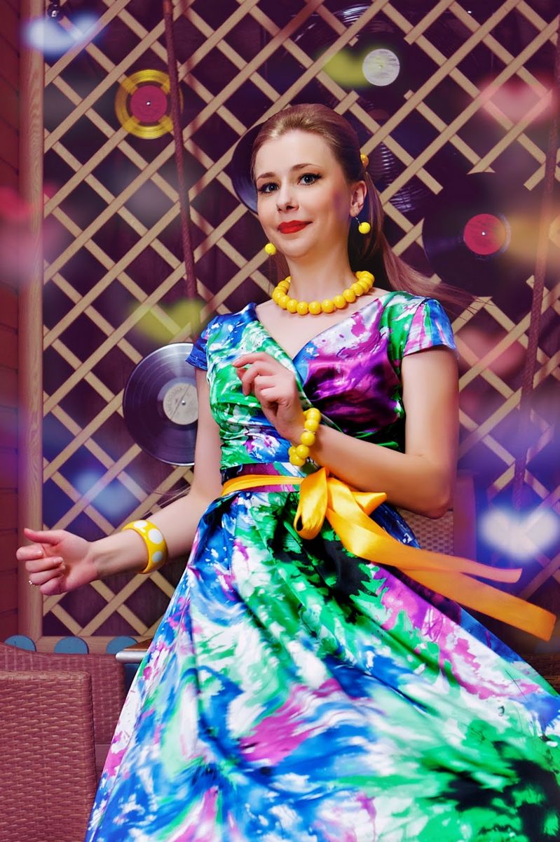 На фото: яркое разноцветное платье в стиле стиляг с желтыми бусами, браслетом и поясом.