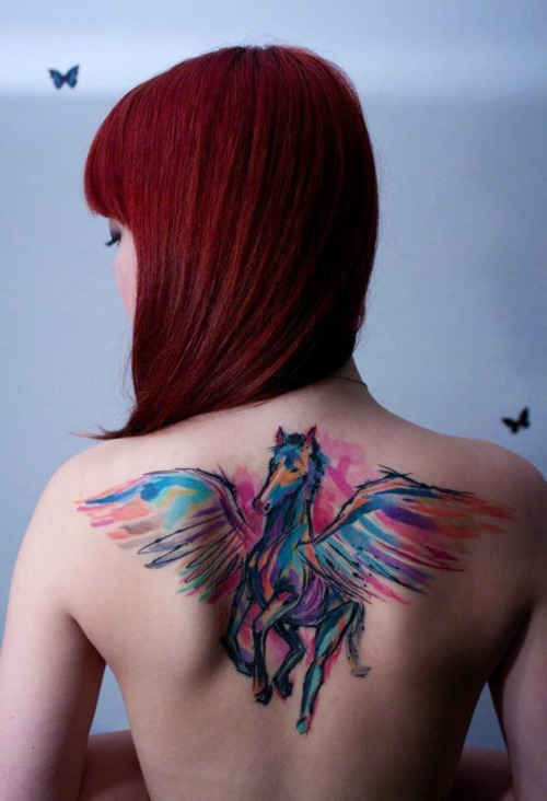 На фото: акварельная татуировка в виде яркой разноцветного коня с крыльями на спине.