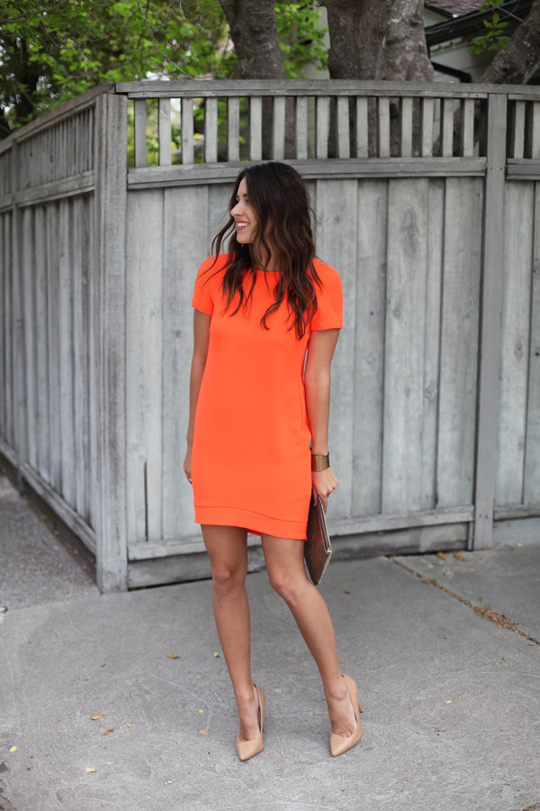 На фото: оранжевое платье прямого покроя, длиной выше колена с коротким рукавом.