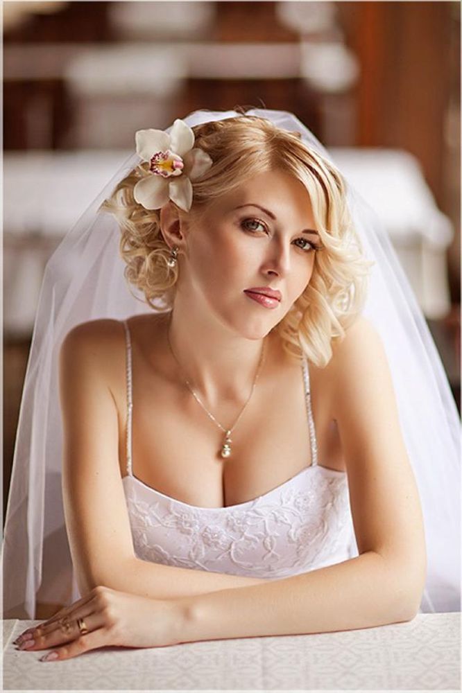 На фото: свадебная короткая причёска  с фатой и с цветком сбоку в волосах.